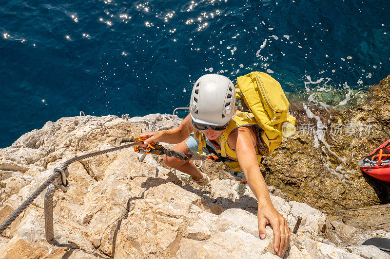 费拉塔岛(Via Ferrata)上的攀登者，年轻的妇女们在攀登海面上的岩石